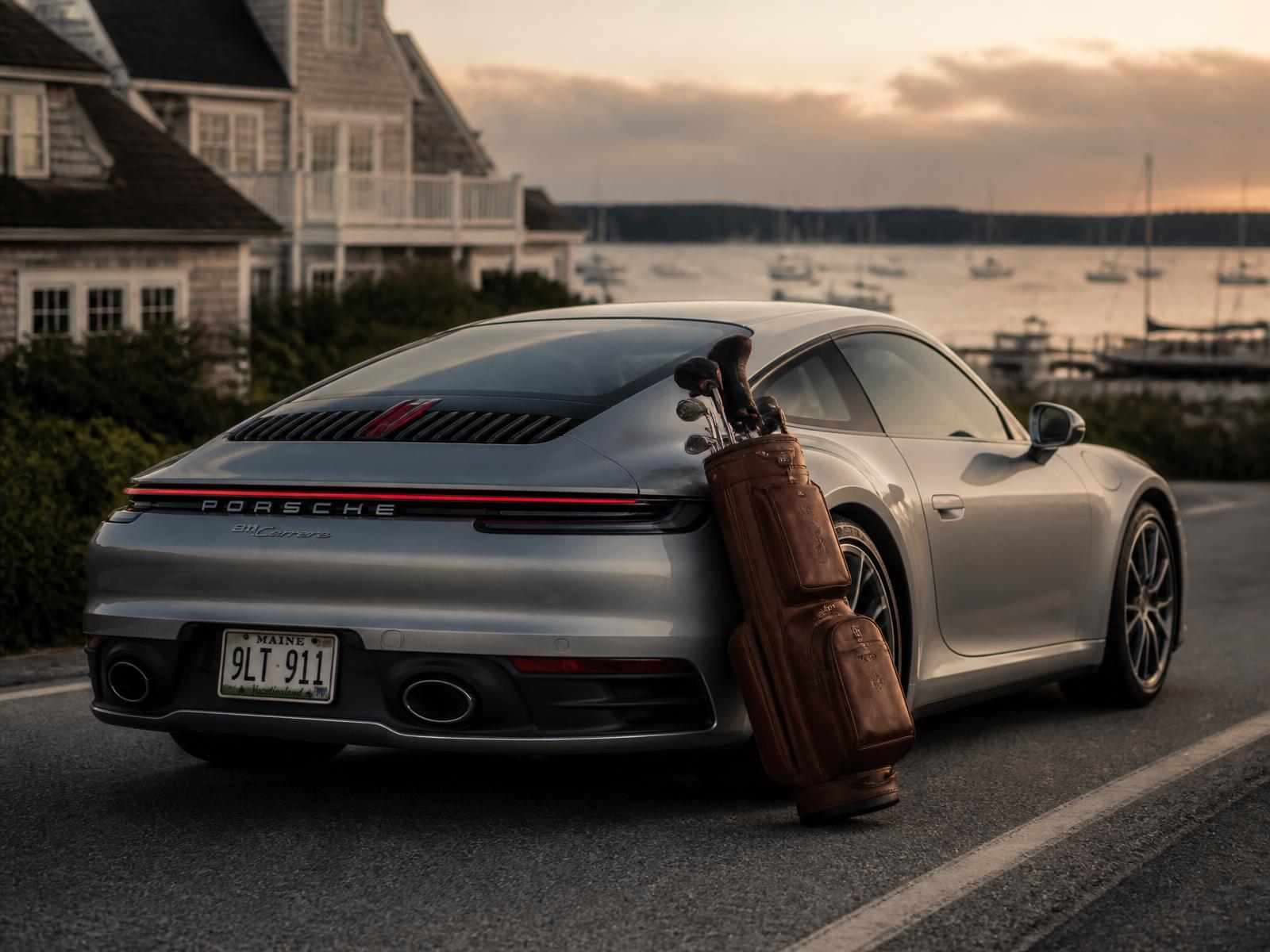 2021 Porsche 911 Carrera on a coastal road at dusk with a leather golf bag